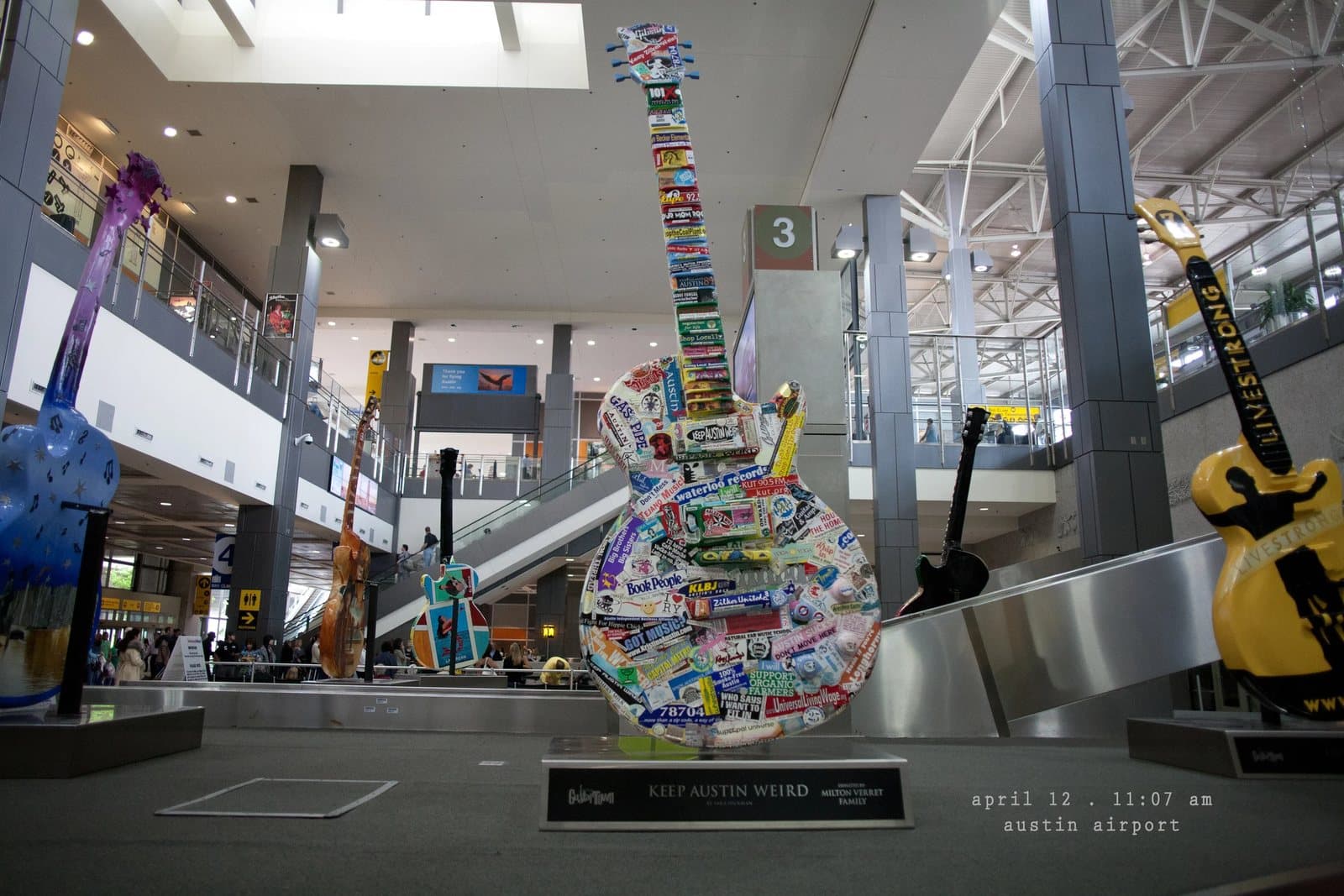 Giant decorated guitar sculptures in the Austin airport terminal, with a Keep Austin Weird sign.