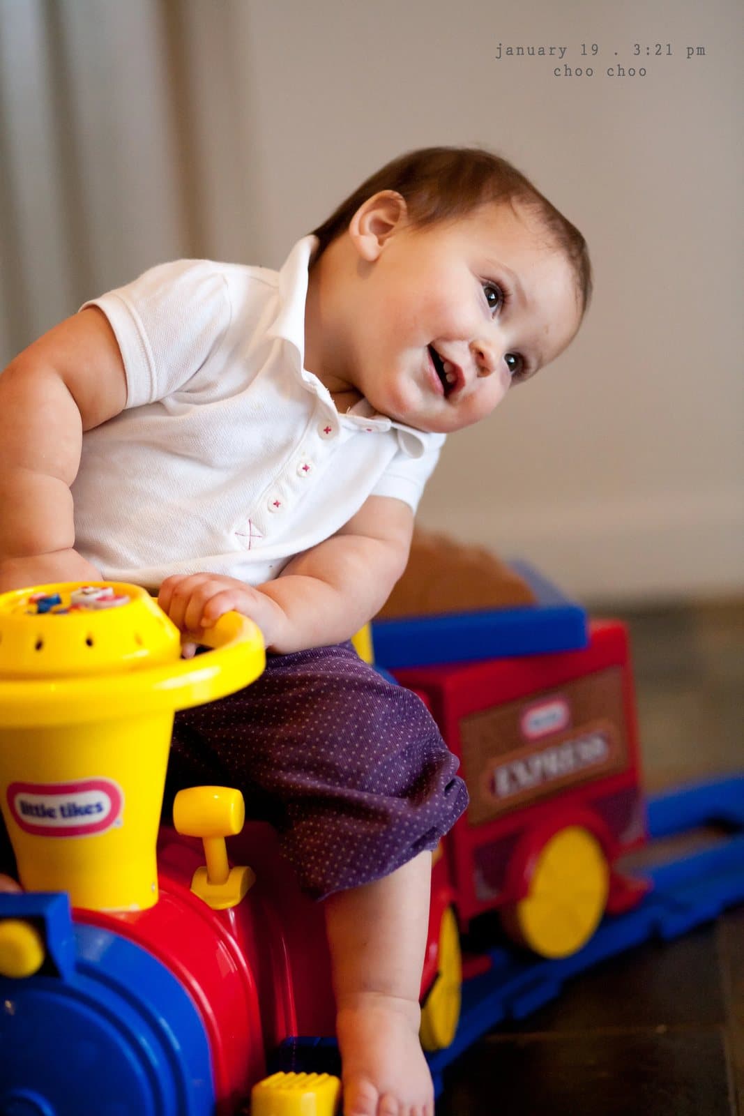 A smiling baby rides a Little Tikes Express toy train, captioned choo choo.