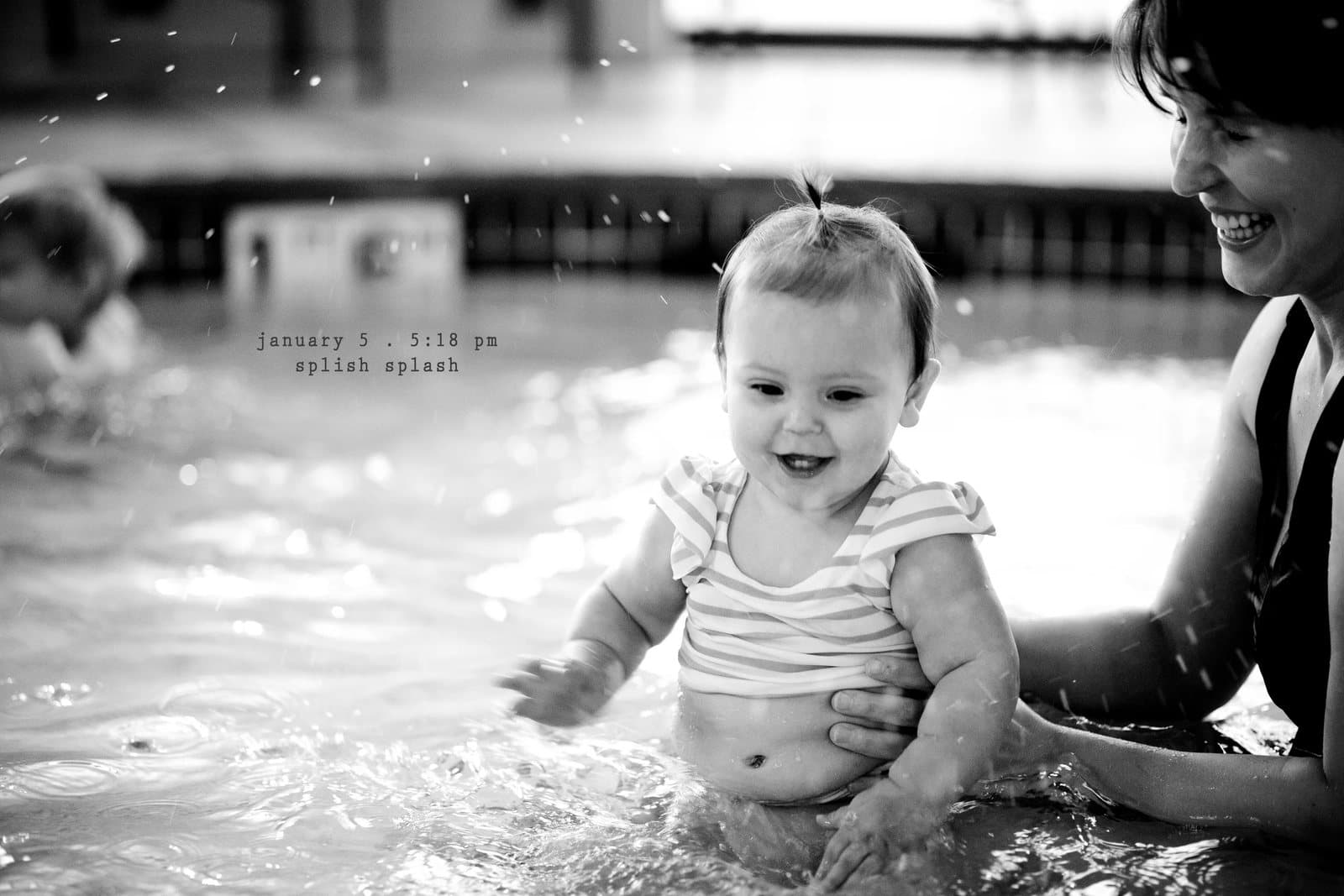 A smiling baby splashes in a pool with a woman's help, captioned splish splash.