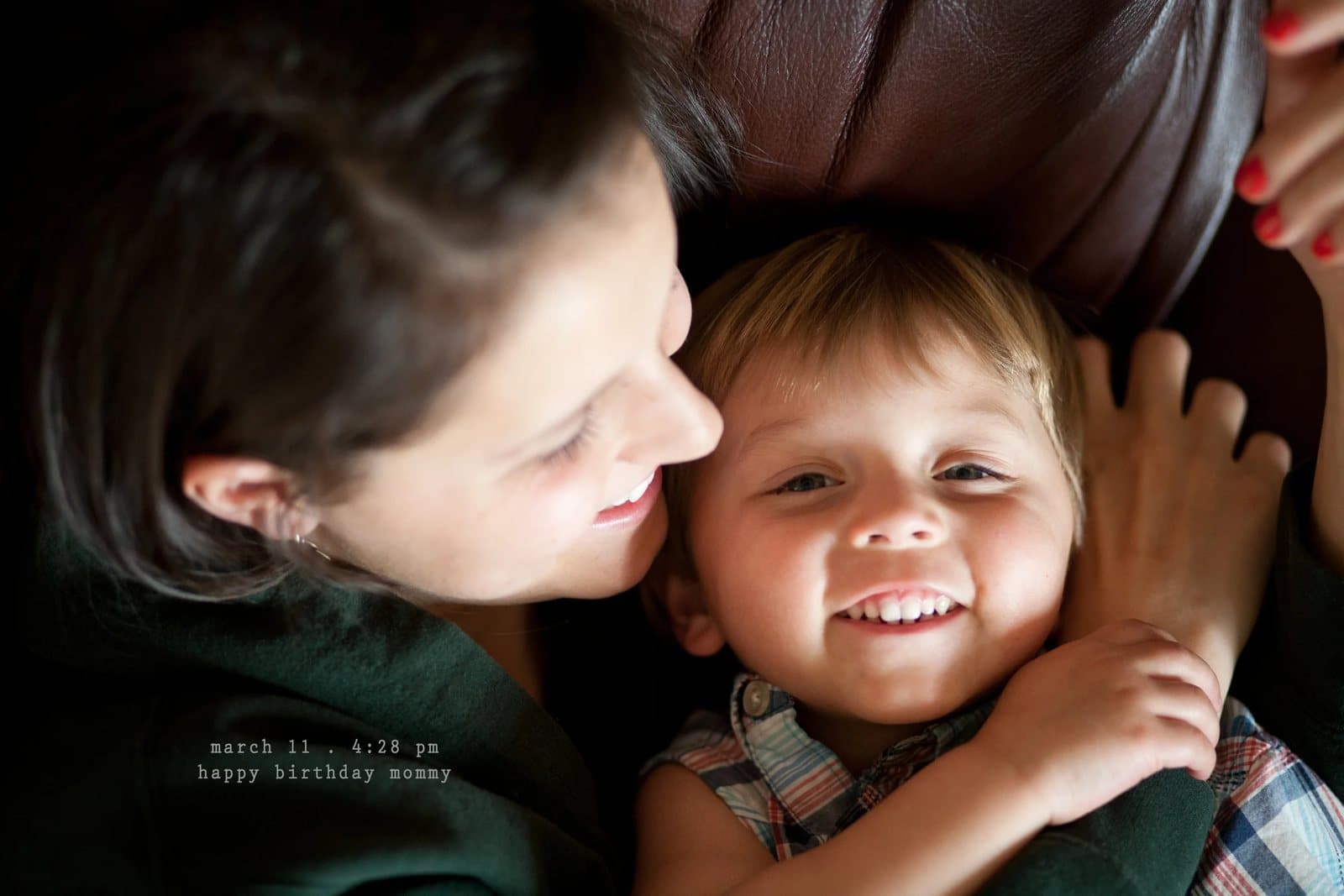 A woman cuddles a grinning toddler cheek to cheek, captioned happy birthday mommy.