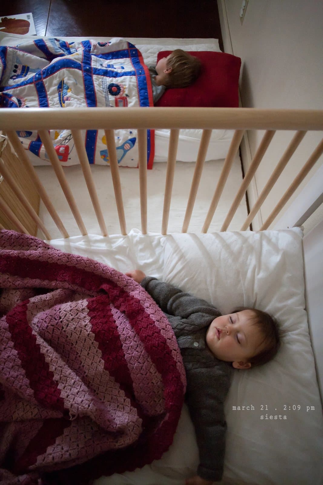 Two children nap, one in a bed and a baby in a crib, captioned siesta.