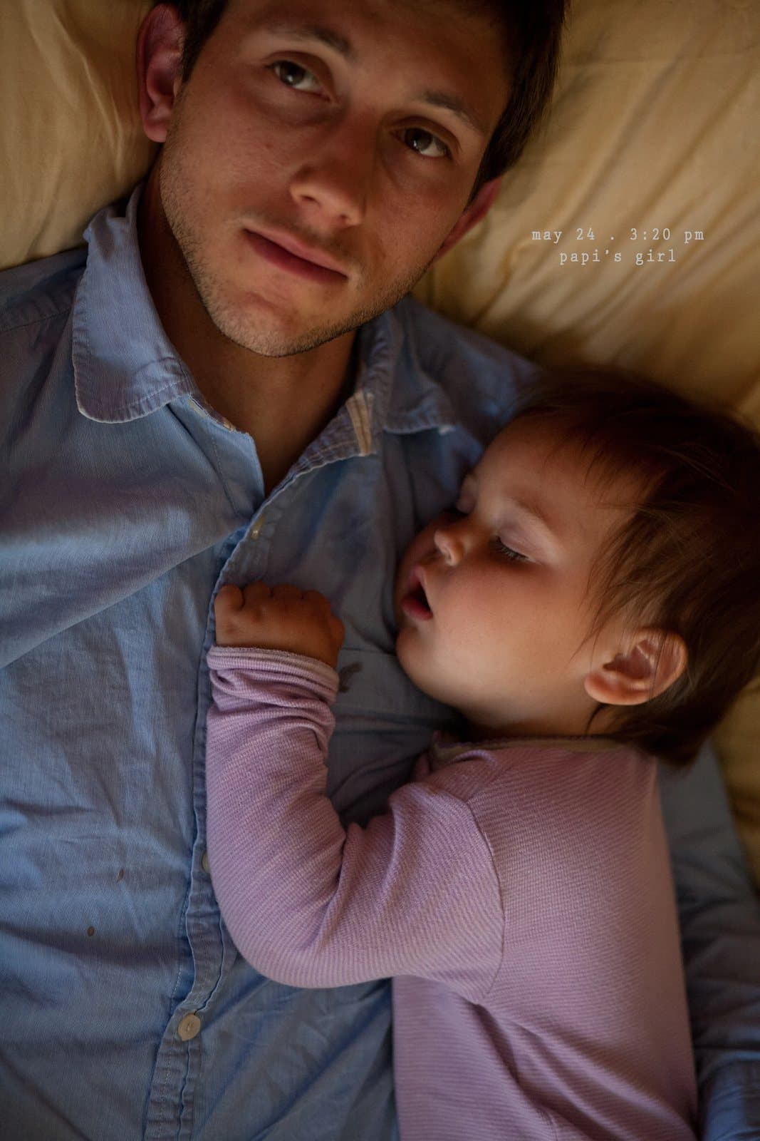 A man lies in bed with a sleeping baby on his chest, captioned papi's girl.