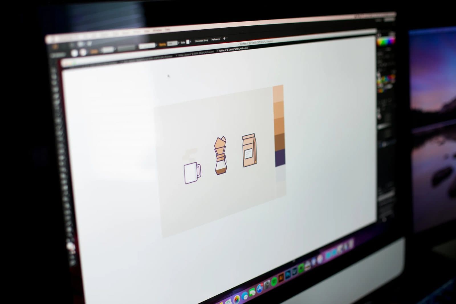 A monitor in Kyle's studio shows coffee icons in progress beside a warm color palette.