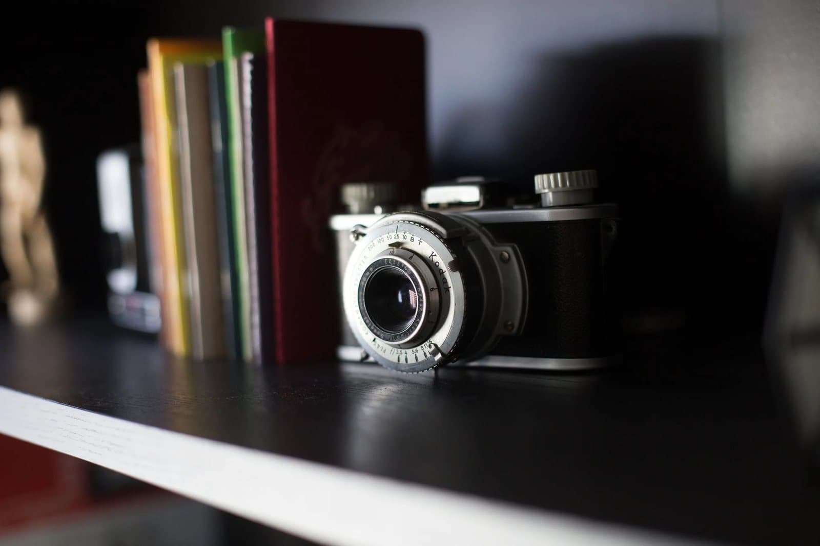 A vintage camera rests beside a row of books on a dark shelf in Kyle's studio.