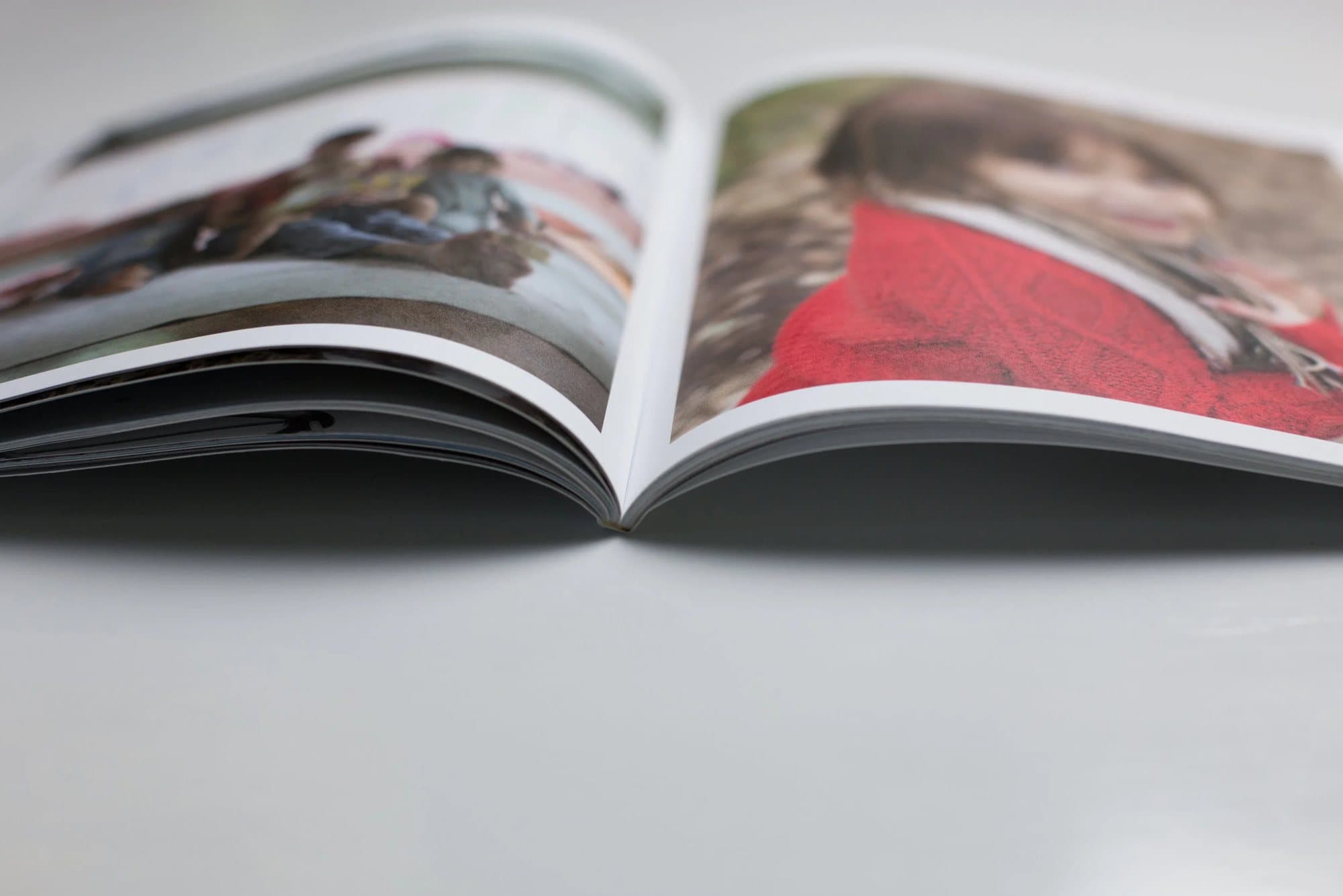Close-up of a printed 3vies magazine lying open, showing its uncoated pages and photo spreads.