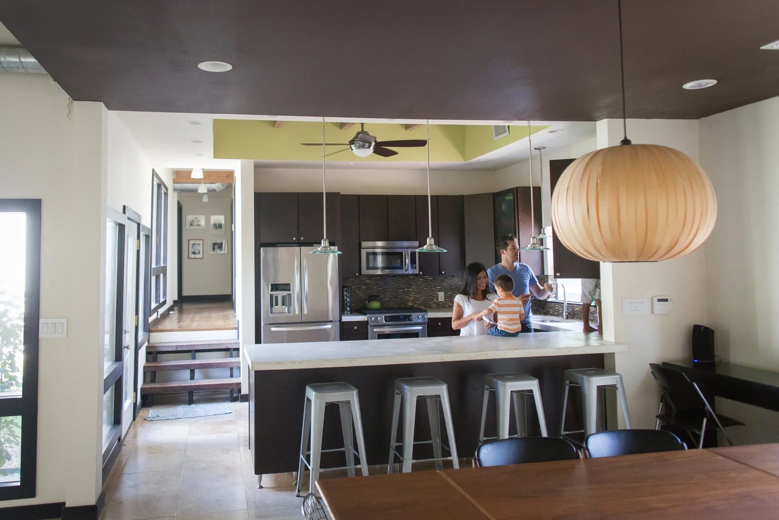 The open kitchen of the house on Morning Side, with the parents and a child at the counter.