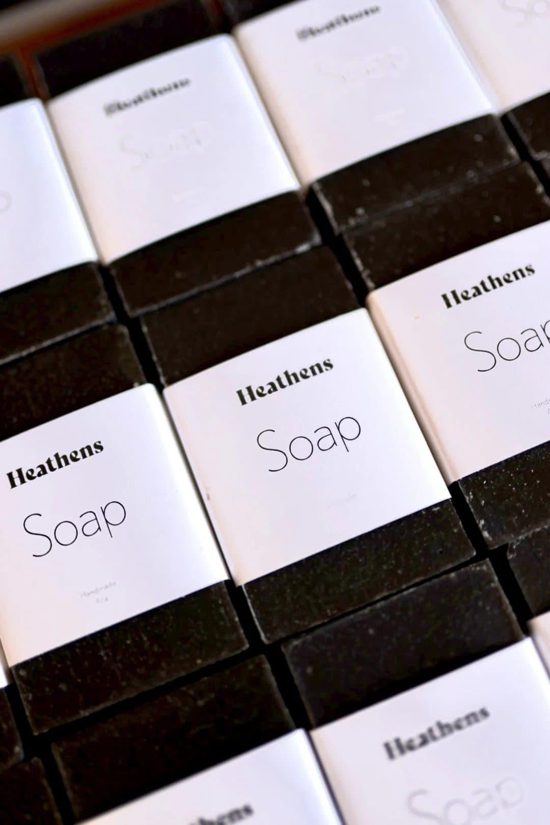 Rows of Heathens Soap bars in white wrappers and black soap, from the House of Heathens lifestyle brand.