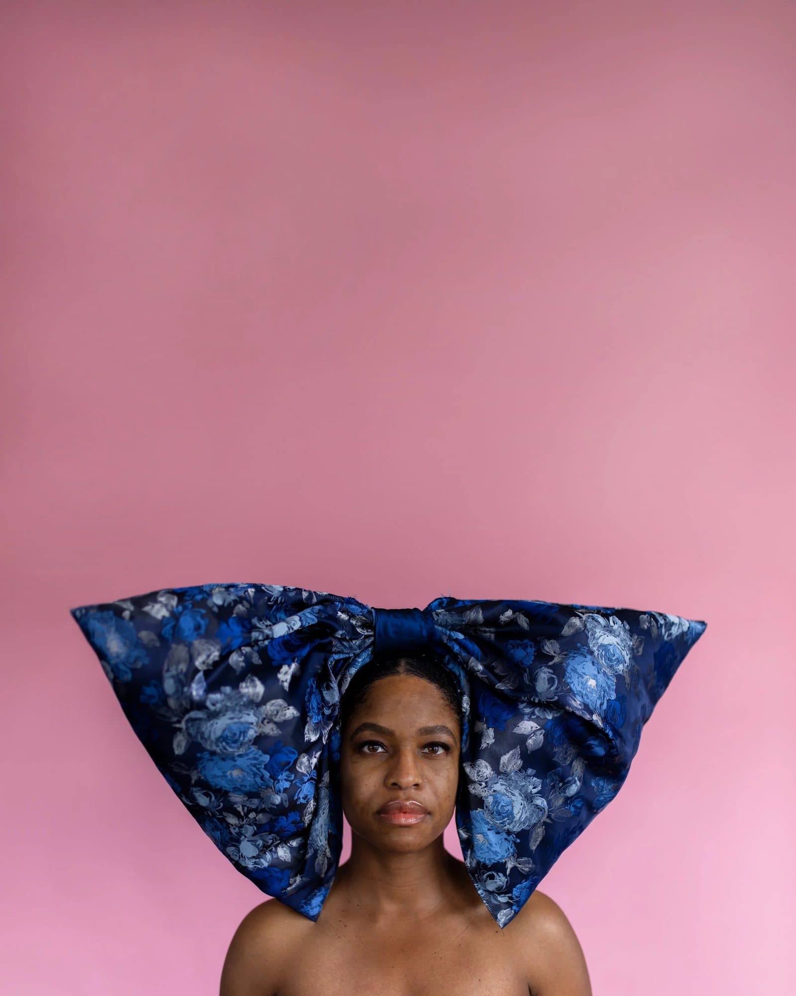 Larissa Leath, featured in Volume 39, wearing an oversized blue floral bow against a pink wall.
