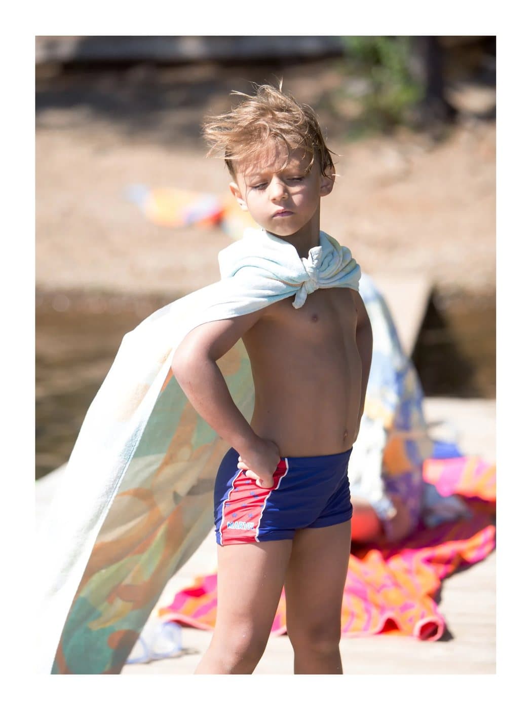Pax, a TIMELESS archival print of a young boy in swim trunks wearing a towel cape on a dock.