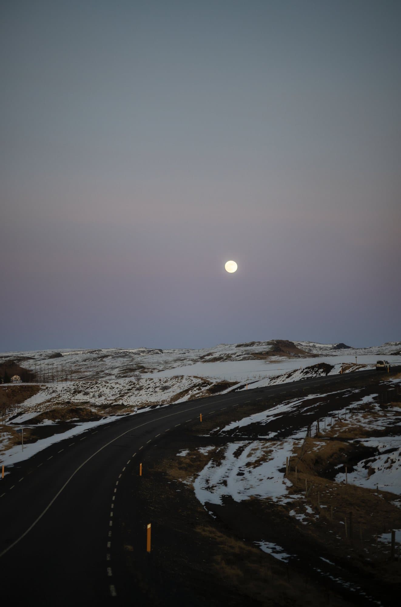 Photo handout of a full moon rising over a winding road through snowy Icelandic hills.