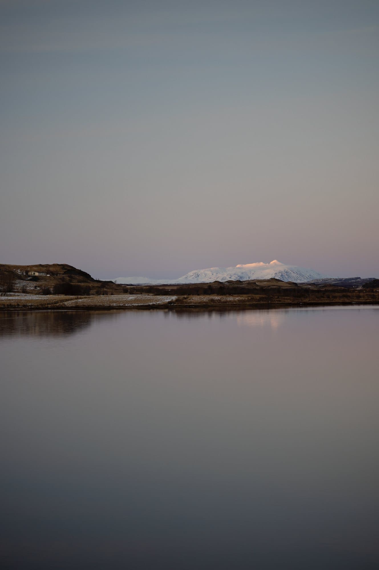 Photo handout of a calm lake reflecting a distant snowy mountain at dusk in Iceland.