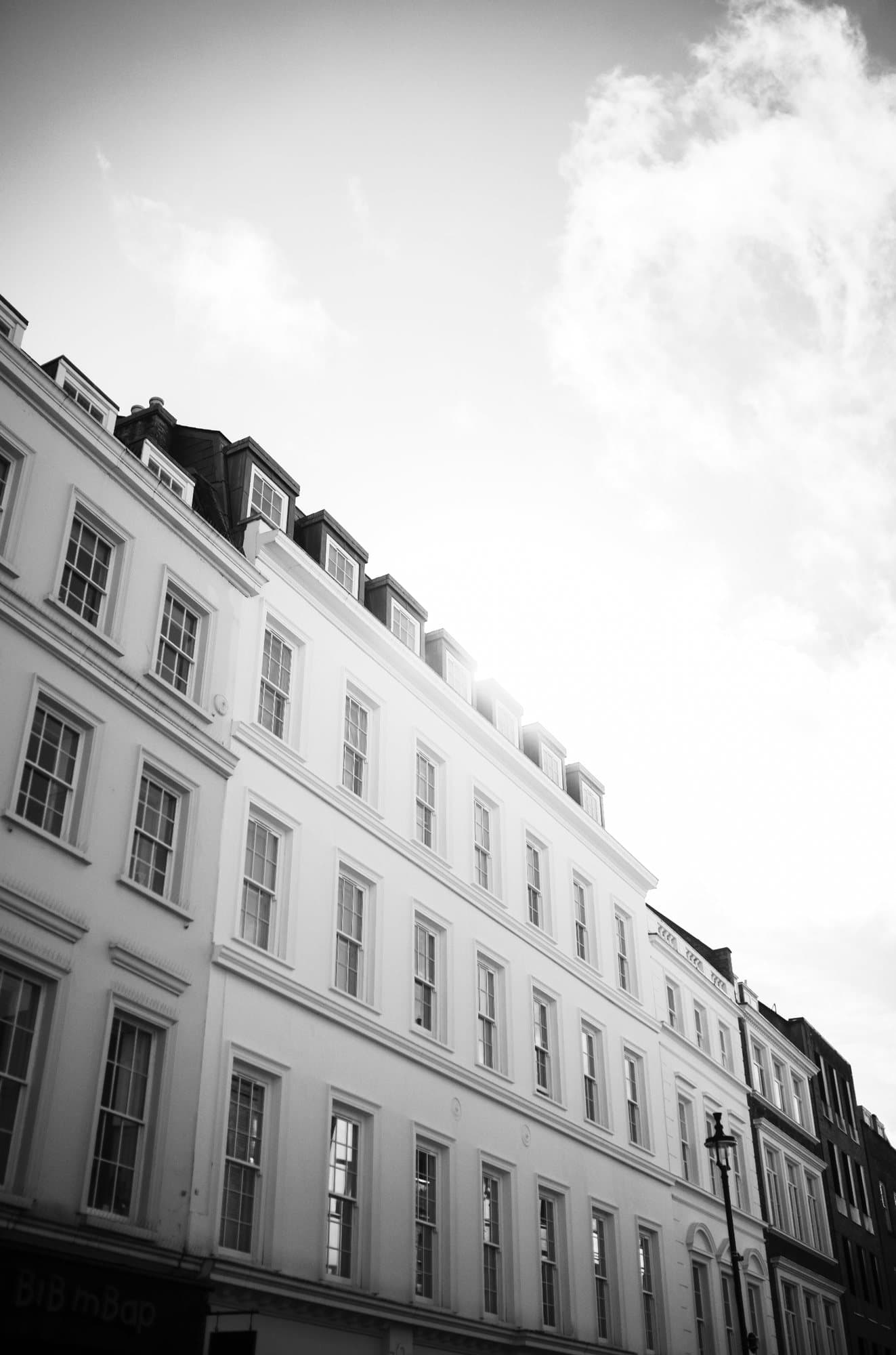 Black and white photo handout of a row of white London townhouses under bright clouds.