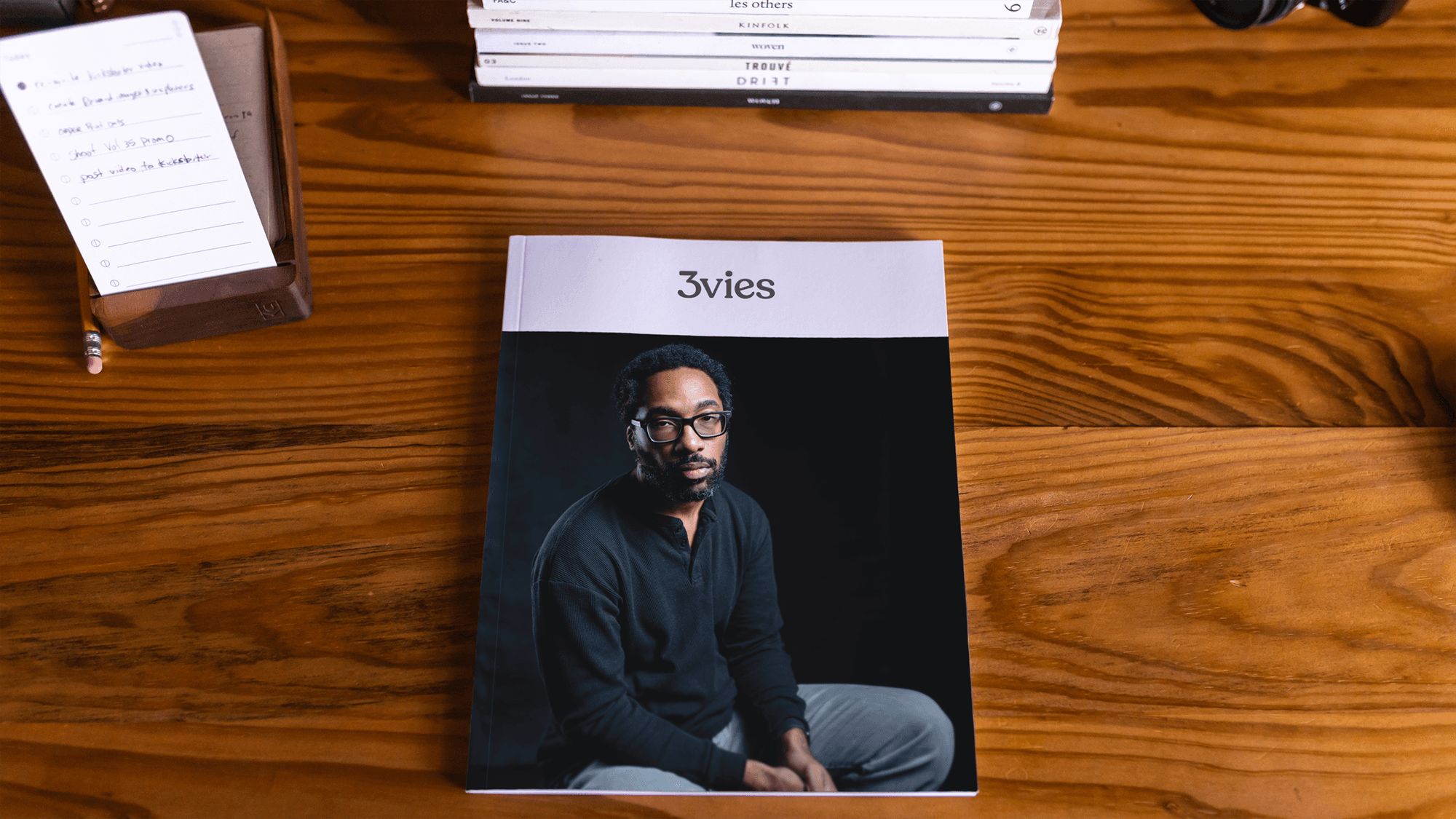 Volume 35 lying on a wooden desk beside a stack of indie magazines and a handwritten list.