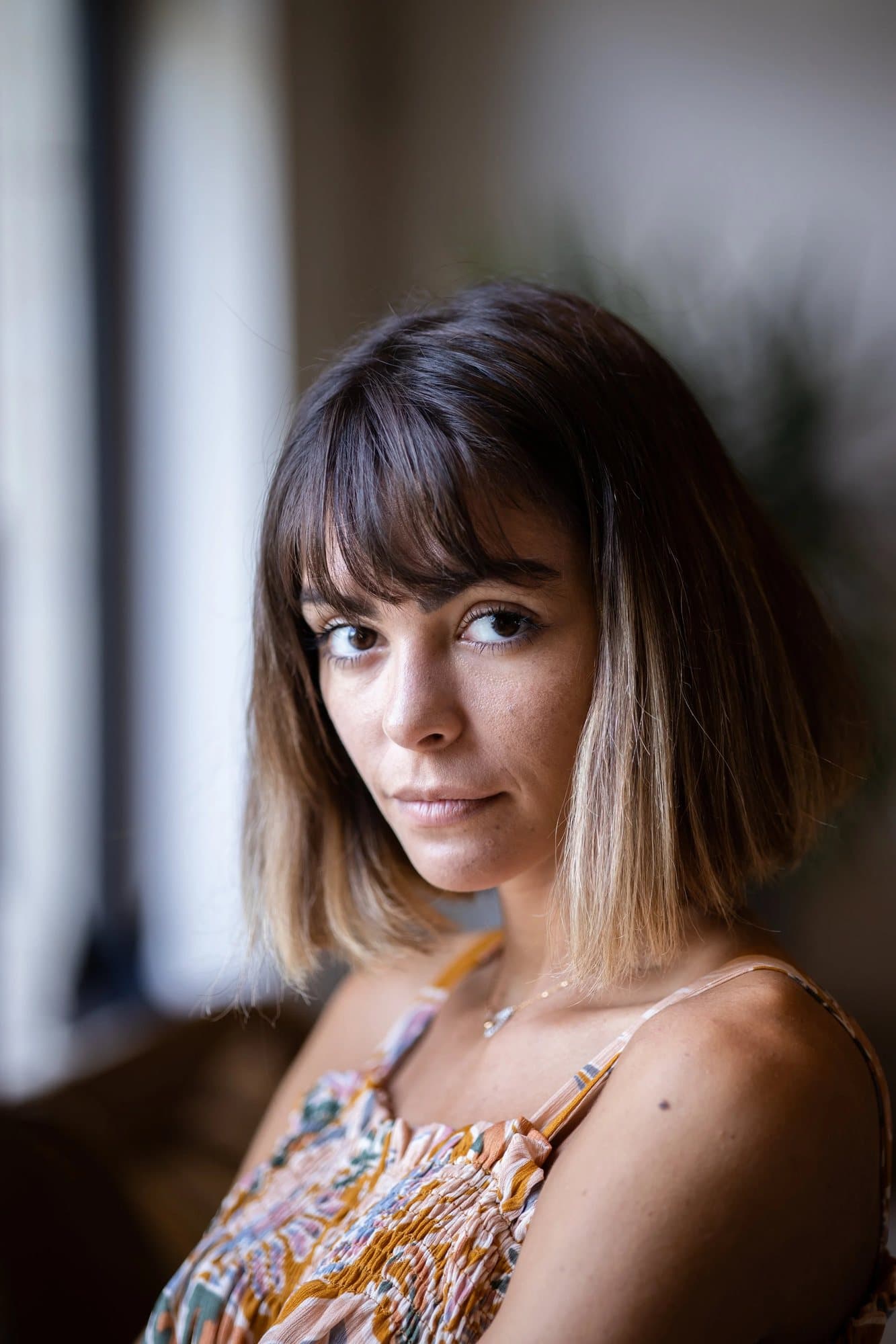 Olly Pryce in a floral sundress, her blond-tipped bob framing a direct gaze.
