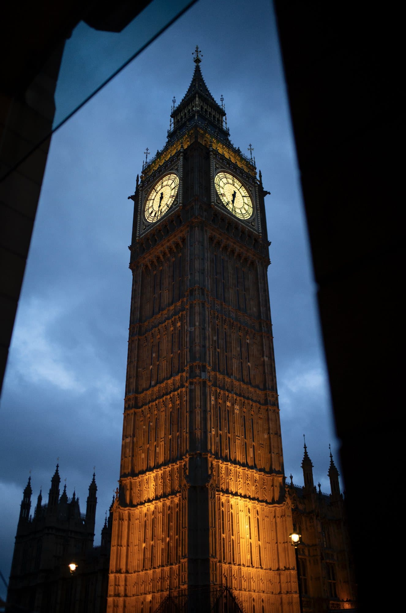 Big Ben's illuminated clock tower against a deep blue evening sky in London.